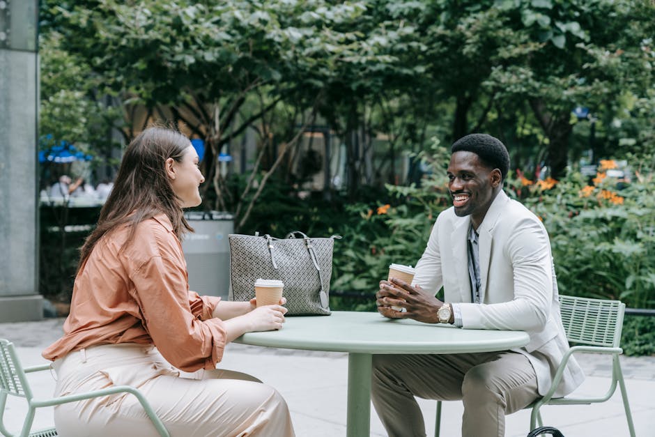 Two well-dressed people enjoying coffee and conversation at an outdoor cafe